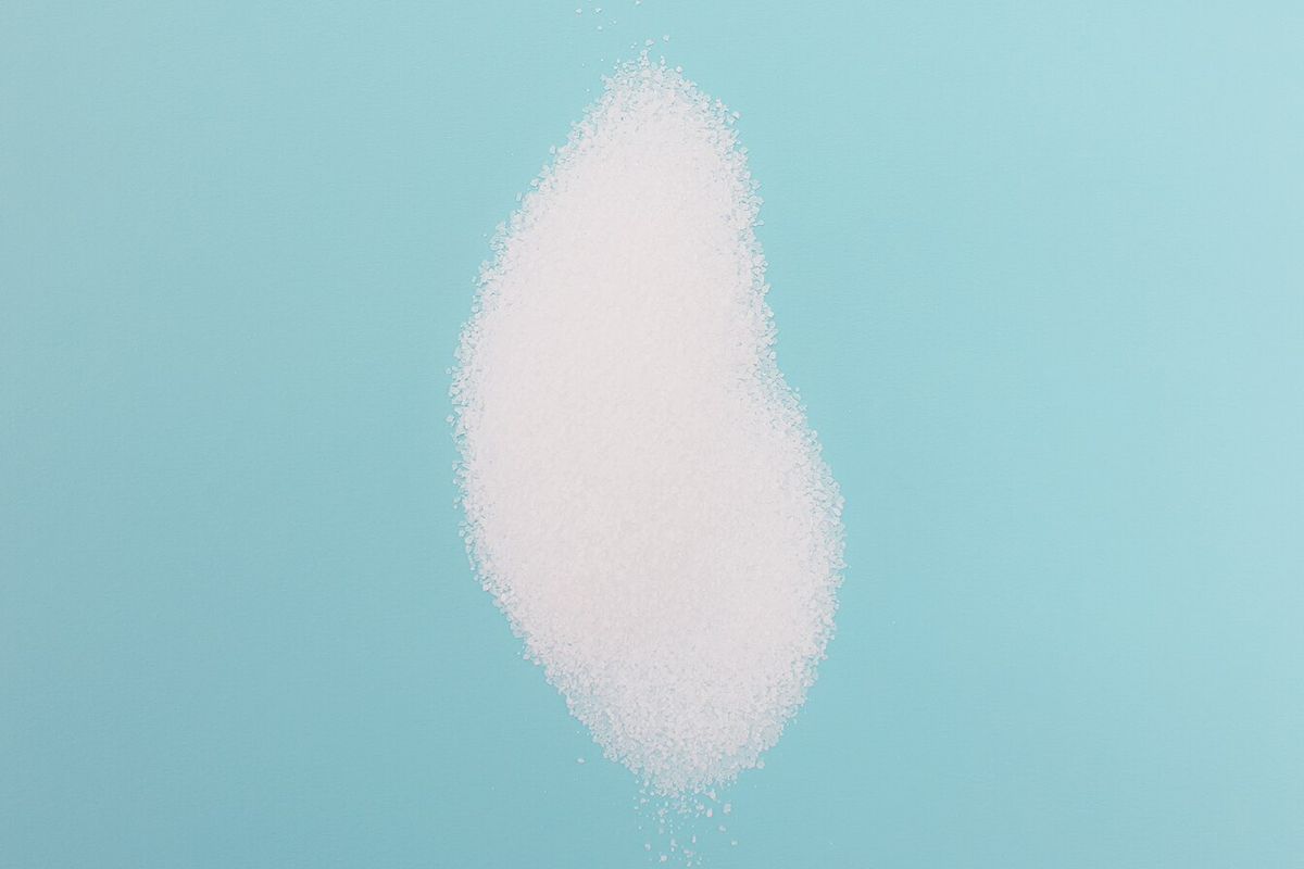 A small pile of fine white table salt on a blue surface