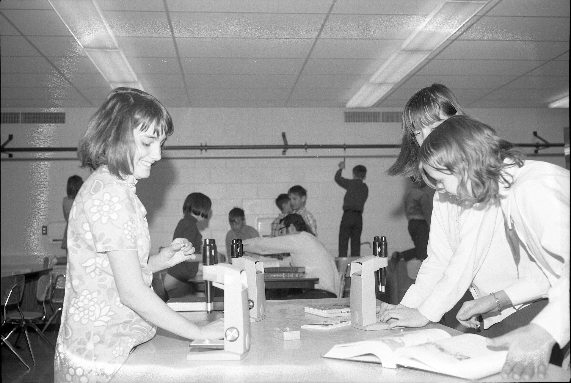 Students in a science classroom leaning over a table to look through microscopes