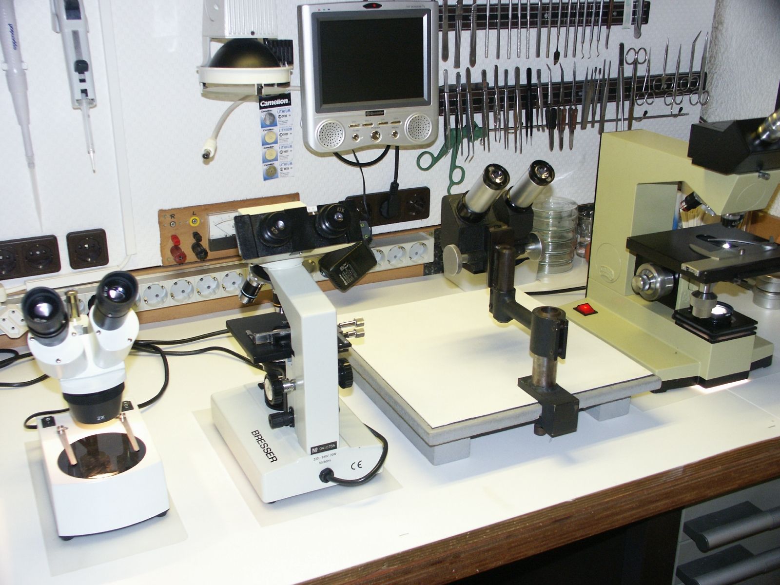 Several microscopes set out on a white lab bench