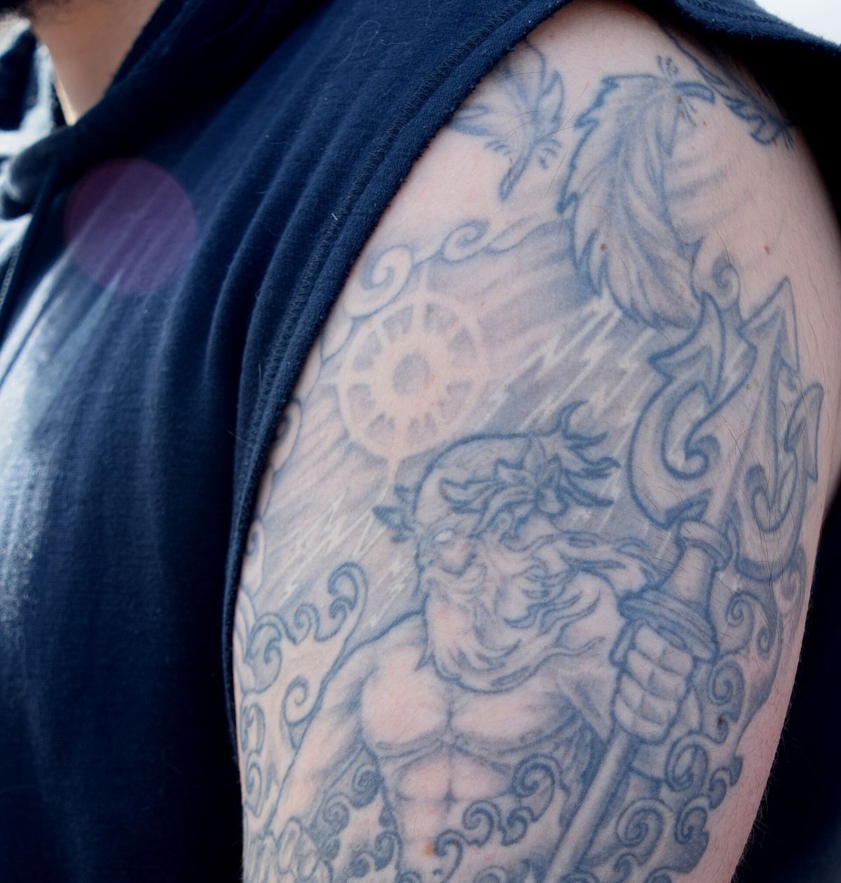 A blue-grey tattoo covering a person's upper arm