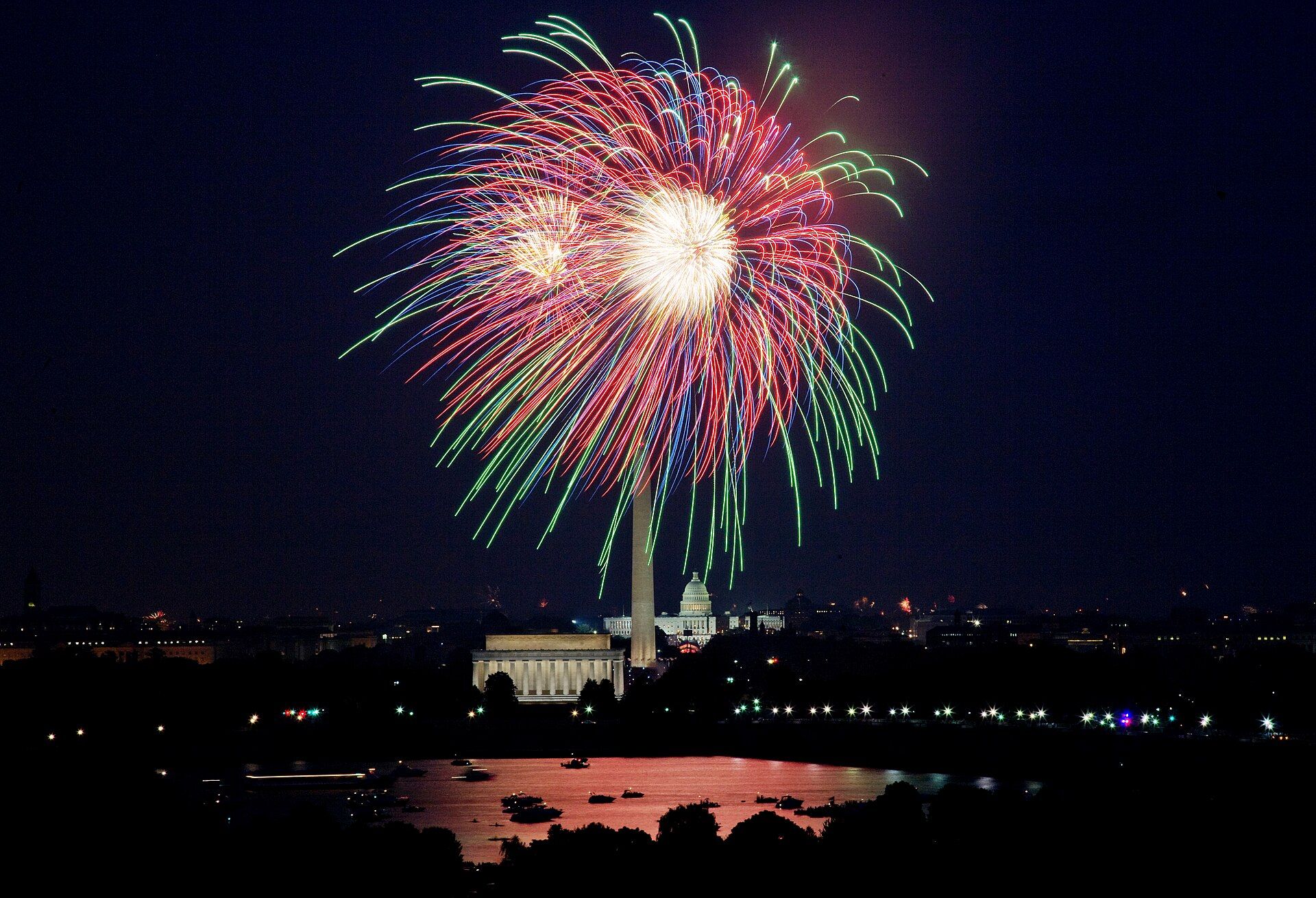 Red, green and white fireworks bursting in the night sky over the Washington Monument and the Lincoln Memorial